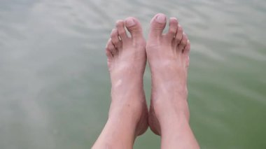 Egzersiz yapan ve nehir kenarında ayaklarını esneten bir adam..