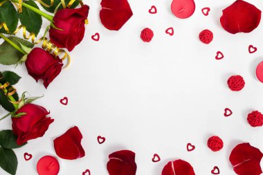 Composition of red roses, rose petals, sequin hearts, candles, gold ribbons on white background. Content for Birthday, Valentines Day, Womens day, Mothers day. Flat lay, top view, close up, copy space