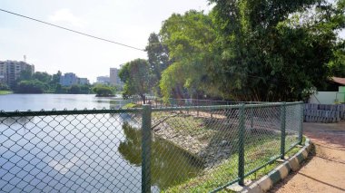 Bangalore, Karnataka, Hindistan-18 Eylül 2022: Yeşil kaplı ve bulutlu gökyüzü ve şehir altyapısı açık iblur gölünün yürüyüş şeridi.