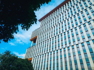 Benzersiz alçak açılı bina perspektifi. Parlak güneş modern binanın camına yansıyor.