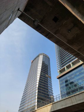 Mavi gökyüzünde güneş ışınları ile parlak güneşli bir günde gökdelen cam cepheler.