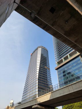 Mavi gökyüzünde güneş ışınları ile parlak güneşli bir günde gökdelen cam cepheler.