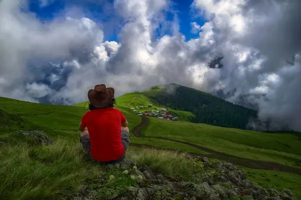 Tourist watching a village among the clouds. Traveler watching the landscape on the plateau.
