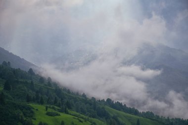 Gün batımı, bir fırtına koparken platoda son ışık demetlerini atıyor. Platonun üzerindeki siste bir köy.