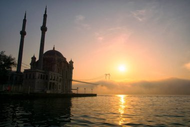 İstanbul 'daki Ortakoy Camii ve Boğaz Köprüsü. Dramatik bir gökyüzü. 15 Temmuz Şehitler Köprüsü sisli. Siste muhteşem İstanbul manzarası.