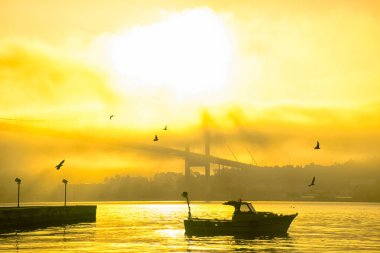 Boğaz 'daki siste bir tekne hareket ediyor. 15 Temmuz Şehitler Köprüsü ve Ortakoy Camii siste.