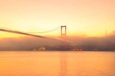 15 Temmuz Şehitler Köprüsü (Boğaz Köprüsü), sis bulutlarında martı ve gün doğumuyla birlikte görülüyor. Sisli boğazda balıkçı tekneleri.