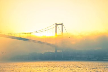 15 Temmuz Şehitler Köprüsü (Boğaz Köprüsü), sis bulutlarında martı ve gün doğumuyla birlikte görülüyor. Sisli boğazda balıkçı tekneleri.