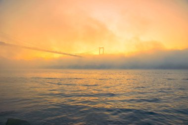 15 Temmuz Şehitler Köprüsü (Boğaz Köprüsü), sis bulutlarında martı ve gün doğumuyla birlikte görülüyor. Sisli boğazda balıkçı tekneleri.