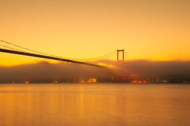 15 Temmuz Şehitler Köprüsü (Boğaz Köprüsü), sis bulutlarında martı ve gün doğumuyla birlikte görülüyor. Sisli boğazda balıkçı tekneleri.