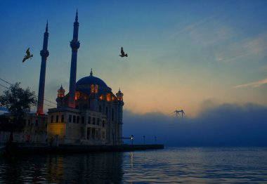 15 Temmuz Şehitler Köprüsü (Boğaz Köprüsü), sis bulutlarında martı ve gün doğumuyla birlikte görülüyor. Ortakoy Camii ve Boğaz Köprüsü 'nden sisli sabah manzarası