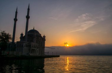 15 Temmuz Şehitler Köprüsü (Boğaz Köprüsü), sis bulutlarında martı ve gün doğumuyla birlikte görülüyor. Ortakoy Camii ve Boğaz Köprüsü 'nden sisli sabah manzarası