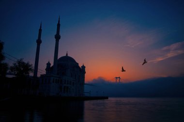 15 Temmuz Şehitler Köprüsü (Boğaz Köprüsü), sis bulutlarında martı ve gün doğumuyla birlikte görülüyor. Ortakoy Camii ve Boğaz Köprüsü 'nden sisli sabah manzarası