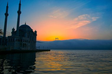 15 Temmuz Şehitler Köprüsü (Boğaz Köprüsü), sis bulutlarında martı ve gün doğumuyla birlikte görülüyor. Ortakoy Camii ve Boğaz Köprüsü 'nden sisli sabah manzarası