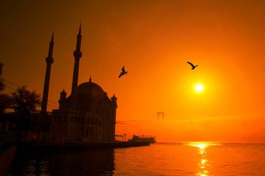 İstanbul 'daki Ortakoy Camii ve Boğaz Köprüsü. Dramatik bir gökyüzü. 15 Temmuz Şehitler Köprüsü sisli. Sisli bir günde Denizdeki Yolcu Gemisi.