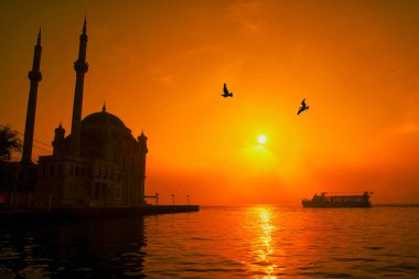 İstanbul 'daki Ortakoy Camii ve Boğaz Köprüsü. Dramatik bir gökyüzü. 15 Temmuz Şehitler Köprüsü sisli. Sisli bir günde Denizdeki Yolcu Gemisi.