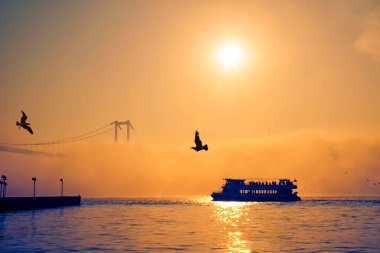 İstanbul 'daki Ortakoy Camii ve Boğaz Köprüsü. Dramatik bir gökyüzü. 15 Temmuz Şehitler Köprüsü sisli. Sisli bir günde Denizdeki Yolcu Gemisi.