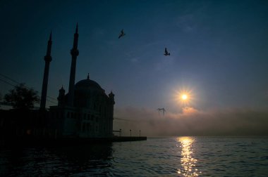15 Temmuz Şehitler Köprüsü (Boğaz Köprüsü), sis bulutlarında martı ve gün doğumuyla birlikte görülüyor. Ortakoy Camii 'nden sisli sabah manzarası ve 15 Şehitler Köprüsü. 