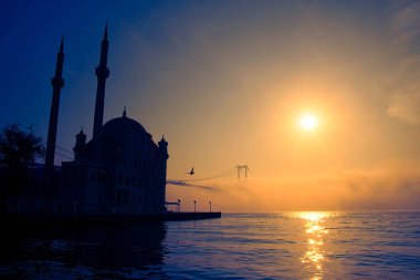 15 Temmuz Şehitler Köprüsü (Boğaz Köprüsü), sis bulutlarında martı ve gün doğumuyla birlikte görülüyor. Ortakoy Camii 'nden sisli sabah manzarası ve 15 Şehitler Köprüsü. 
