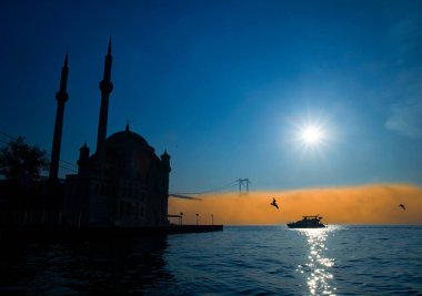 15 Temmuz Şehitler Köprüsü ve Ortaklık Camii 'nin gün doğumu manzarası. 15 Temmuz Şehitler Köprüsü 'nün altında sisli boğazda bir yat hareket ediyor..