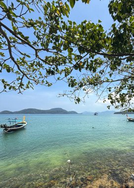 Phuket, Tayland 'daki Panwa Sahili' nden güzel bir deniz manzarası. Görüntü sakin turkuaz sular, yumuşak kumlu kıyılar ve sakin tropikal bir atmosferle huzurlu kıyı manzarasını yakalar.
