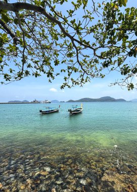 Phuket, Tayland 'daki Panwa Sahili' nden güzel bir deniz manzarası. Görüntü sakin turkuaz sular, yumuşak kumlu kıyılar ve sakin tropikal bir atmosferle huzurlu kıyı manzarasını yakalar.