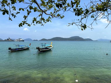 Phuket, Tayland 'daki Panwa Sahili' nden güzel bir deniz manzarası. Görüntü sakin turkuaz sular, yumuşak kumlu kıyılar ve sakin tropikal bir atmosferle huzurlu kıyı manzarasını yakalar.