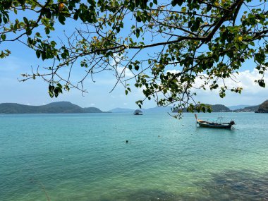 Phuket, Tayland 'daki Panwa Sahili' nden güzel bir deniz manzarası. Görüntü sakin turkuaz sular, yumuşak kumlu kıyılar ve sakin tropikal bir atmosferle huzurlu kıyı manzarasını yakalar.