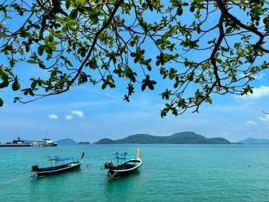 Phuket, Tayland 'daki Panwa Sahili' nden güzel bir deniz manzarası. Görüntü sakin turkuaz sular, yumuşak kumlu kıyılar ve sakin tropikal bir atmosferle huzurlu kıyı manzarasını yakalar.