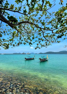 Phuket, Tayland 'daki Panwa Sahili' nden güzel bir deniz manzarası. Görüntü sakin turkuaz sular, yumuşak kumlu kıyılar ve sakin tropikal bir atmosferle huzurlu kıyı manzarasını yakalar.