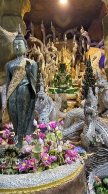 Tayland 'ın Nakhon Nayok kentindeki Wat Maniwong Tapınağı' nın iç manzarasında altın bir Buda heykeli yer almaktadır. Görüntü, bu kutsal mekanın karmaşık tapınak mimarisini, detaylı dekorasyonlarını ve sakin atmosferini gözler önüne seriyor.