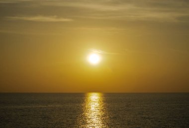 Phuket, Tayland 'da okyanusun üzerinde güzel bir gün batımı, durgun suya yansıyan renkli gökyüzü. Canlı turuncu ve pembe renkleri olan tropik bir cennet. Seyahat ve tatil temaları için mükemmel..