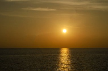Phuket, Tayland 'da okyanusun üzerinde güzel bir gün batımı, durgun suya yansıyan renkli gökyüzü. Canlı turuncu ve pembe renkleri olan tropik bir cennet. Seyahat ve tatil temaları için mükemmel..