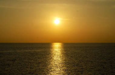 Phuket, Tayland 'da okyanusun üzerinde güzel bir gün batımı, durgun suya yansıyan renkli gökyüzü. Canlı turuncu ve pembe renkleri olan tropik bir cennet. Seyahat ve tatil temaları için mükemmel..