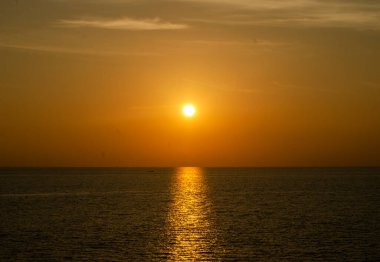 Phuket, Tayland 'da okyanusun üzerinde güzel bir gün batımı, durgun suya yansıyan renkli gökyüzü. Canlı turuncu ve pembe renkleri olan tropik bir cennet. Seyahat ve tatil temaları için mükemmel..