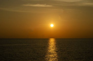 Phuket, Tayland 'da okyanusun üzerinde güzel bir gün batımı, durgun suya yansıyan renkli gökyüzü. Canlı turuncu ve pembe renkleri olan tropik bir cennet. Seyahat ve tatil temaları için mükemmel..
