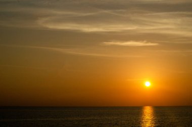 Phuket, Tayland 'da okyanusun üzerinde güzel bir gün batımı, durgun suya yansıyan renkli gökyüzü. Canlı turuncu ve pembe renkleri olan tropik bir cennet. Seyahat ve tatil temaları için mükemmel..