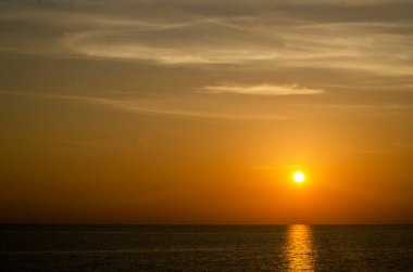 Phuket, Tayland 'da okyanusun üzerinde güzel bir gün batımı, durgun suya yansıyan renkli gökyüzü. Canlı turuncu ve pembe renkleri olan tropik bir cennet. Seyahat ve tatil temaları için mükemmel..