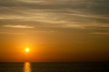Phuket, Tayland 'da okyanusun üzerinde güzel bir gün batımı, durgun suya yansıyan renkli gökyüzü. Canlı turuncu ve pembe renkleri olan tropik bir cennet. Seyahat ve tatil temaları için mükemmel..