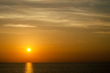 Phuket, Tayland 'da okyanusun üzerinde güzel bir gün batımı, durgun suya yansıyan renkli gökyüzü. Canlı turuncu ve pembe renkleri olan tropik bir cennet. Seyahat ve tatil temaları için mükemmel..