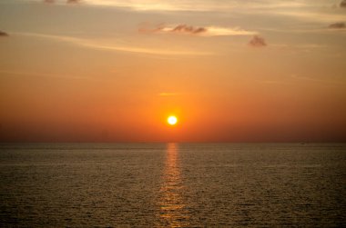 Phuket, Tayland 'da okyanusun üzerinde güzel bir gün batımı, durgun suya yansıyan renkli gökyüzü. Canlı turuncu ve pembe renkleri olan tropik bir cennet. Seyahat ve tatil temaları için mükemmel..