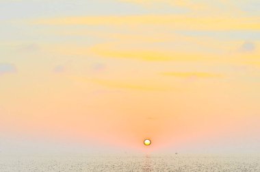 Phuket, Tayland 'da okyanusun üzerinde güzel bir gün batımı, durgun suya yansıyan renkli gökyüzü. Canlı turuncu ve pembe renkleri olan tropik bir cennet. Seyahat ve tatil temaları için mükemmel..