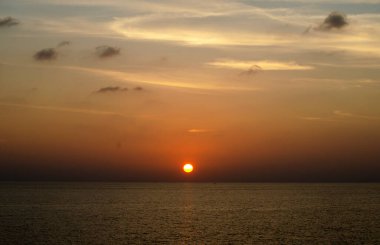Phuket, Tayland 'da okyanusun üzerinde güzel bir gün batımı, durgun suya yansıyan renkli gökyüzü. Canlı turuncu ve pembe renkleri olan tropik bir cennet. Seyahat ve tatil temaları için mükemmel..