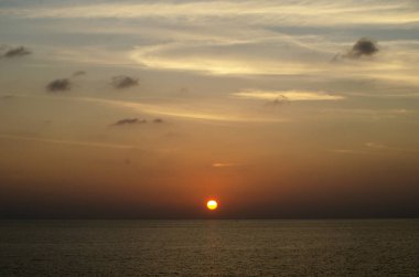 Phuket, Tayland 'da okyanusun üzerinde güzel bir gün batımı, durgun suya yansıyan renkli gökyüzü. Canlı turuncu ve pembe renkleri olan tropik bir cennet. Seyahat ve tatil temaları için mükemmel..
