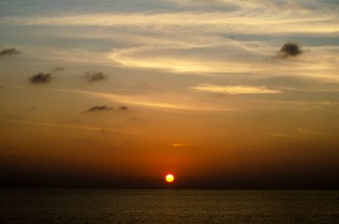 Phuket, Tayland 'da okyanusun üzerinde güzel bir gün batımı, durgun suya yansıyan renkli gökyüzü. Canlı turuncu ve pembe renkleri olan tropik bir cennet. Seyahat ve tatil temaları için mükemmel..
