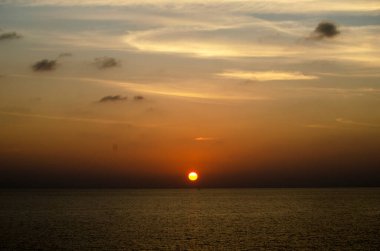 Phuket, Tayland 'da okyanusun üzerinde güzel bir gün batımı, durgun suya yansıyan renkli gökyüzü. Canlı turuncu ve pembe renkleri olan tropik bir cennet. Seyahat ve tatil temaları için mükemmel..