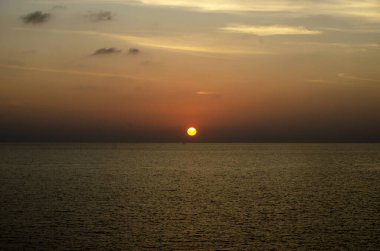 Phuket, Tayland 'da okyanusun üzerinde güzel bir gün batımı, durgun suya yansıyan renkli gökyüzü. Canlı turuncu ve pembe renkleri olan tropik bir cennet. Seyahat ve tatil temaları için mükemmel..