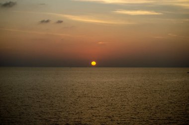 Phuket, Tayland 'da okyanusun üzerinde güzel bir gün batımı, durgun suya yansıyan renkli gökyüzü. Canlı turuncu ve pembe renkleri olan tropik bir cennet. Seyahat ve tatil temaları için mükemmel..