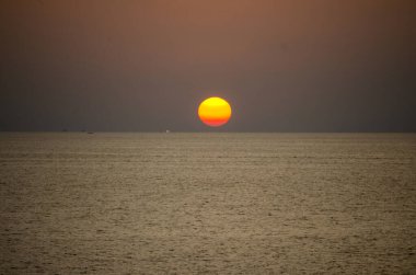 Phuket, Tayland 'da okyanusun üzerinde güzel bir gün batımı, durgun suya yansıyan renkli gökyüzü. Canlı turuncu ve pembe renkleri olan tropik bir cennet. Seyahat ve tatil temaları için mükemmel..