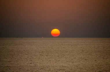 Phuket, Tayland 'da okyanusun üzerinde güzel bir gün batımı, durgun suya yansıyan renkli gökyüzü. Canlı turuncu ve pembe renkleri olan tropik bir cennet. Seyahat ve tatil temaları için mükemmel..